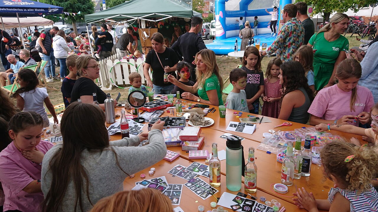 Kinder beim Basteln und Schminken am Tisch auf dem Sommerfest