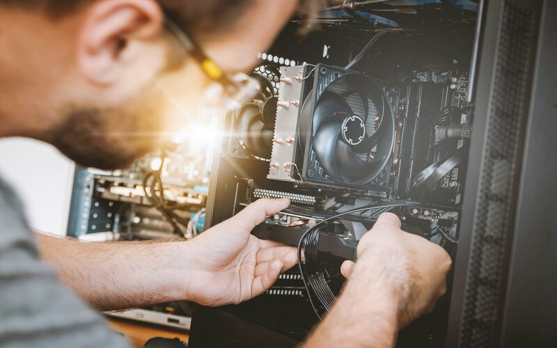 Techniker baut eine Grafikkarte in einen PC ein